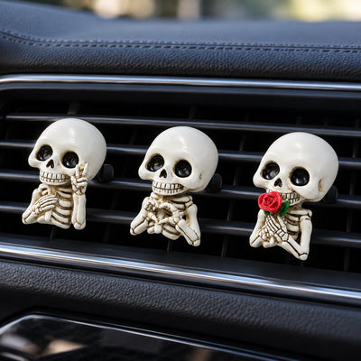 Three smiling skeleton car air vent clips with peace sign, heart hands and red rose designs