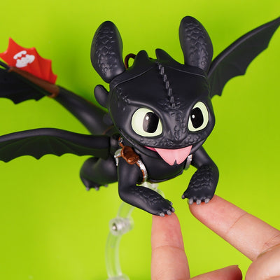 Toothless figure with tongue-out face and extended wings supported by fingertips