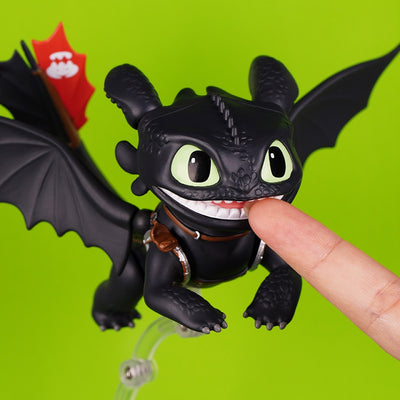 Close-up of articulated Toothless figure with fingertip demonstrating the movable mouth