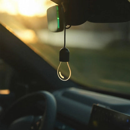 CARMOJ Glowing light bulb car charm hanging inside a car with the light off