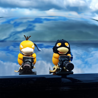 Hooded and hoodless Gatling Psyduck ornaments displayed side by side on a glossy car roof
